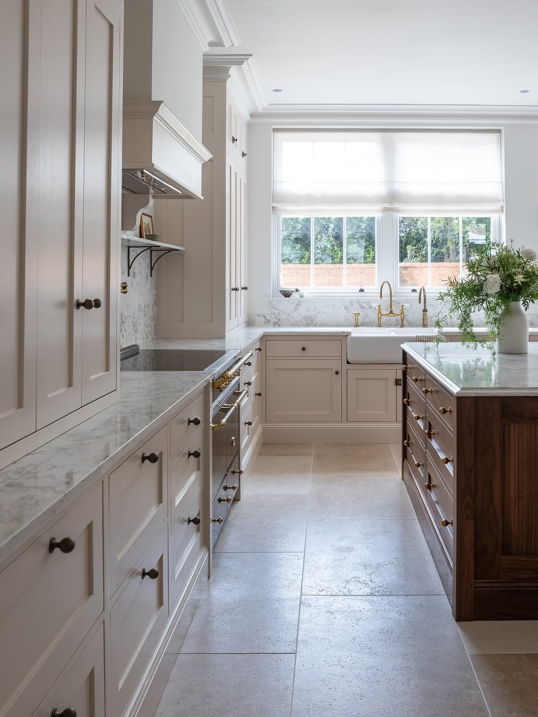 Beige cabinetry fills every wall in-frame beside marble and brass